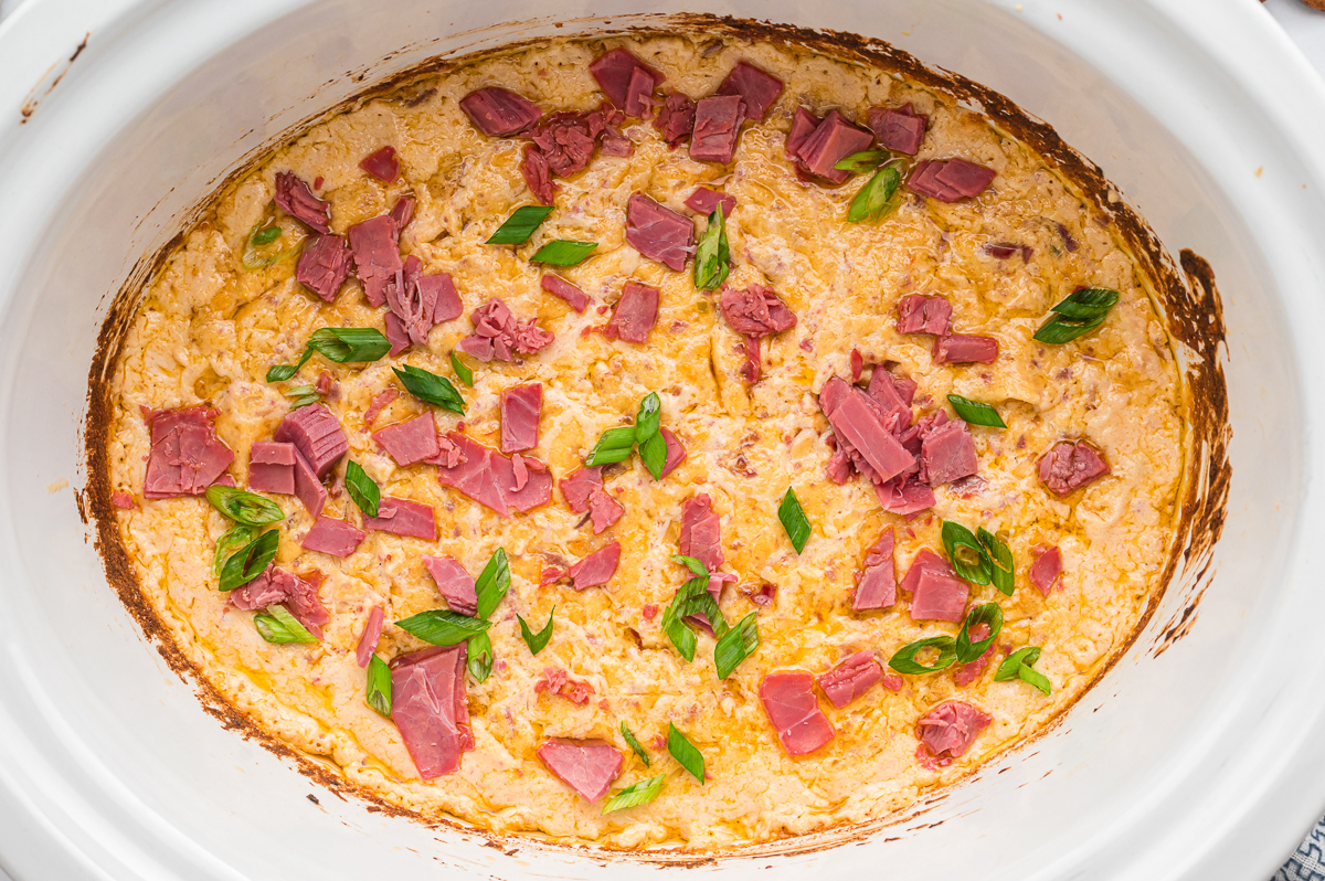 Cooked rueben dip with green onions and corned beef on top.