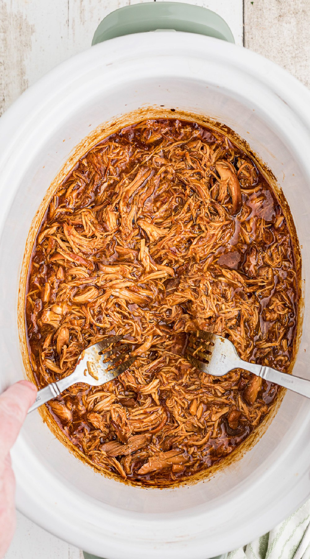 2 forks shredding chicken in a slow cooker.