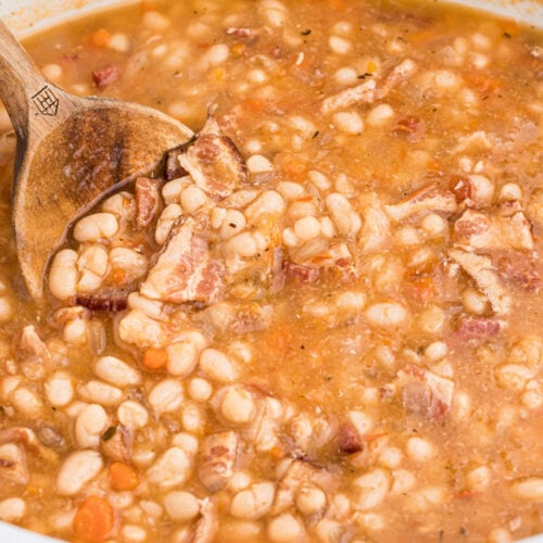 Bean and bacon soup (campell's copycat) in slow cooker with a wooden spoon.