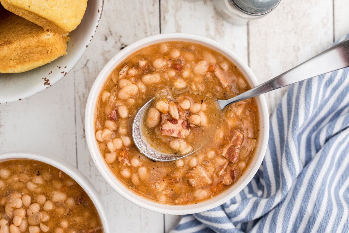 Bowl of bean soup with metal spoon in it.