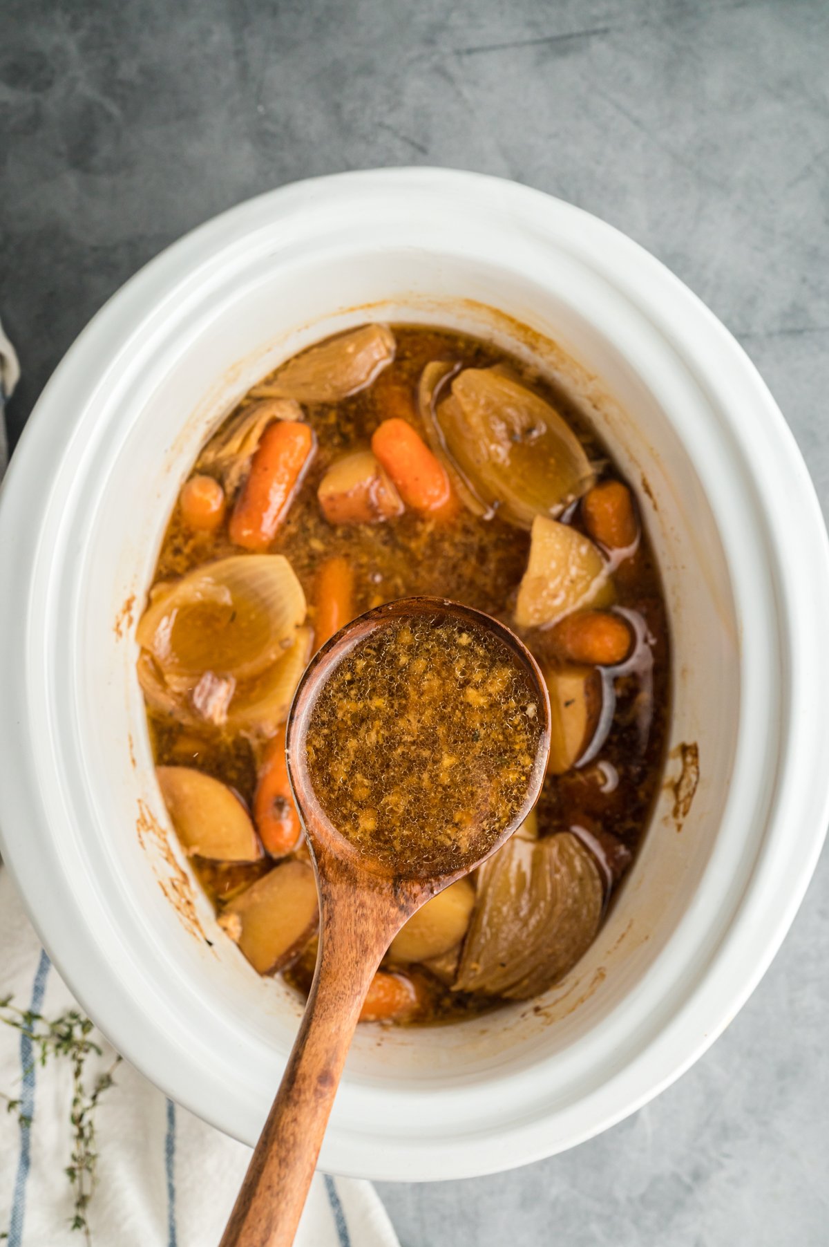 drippings being taken out of slow cooker to make gravy.