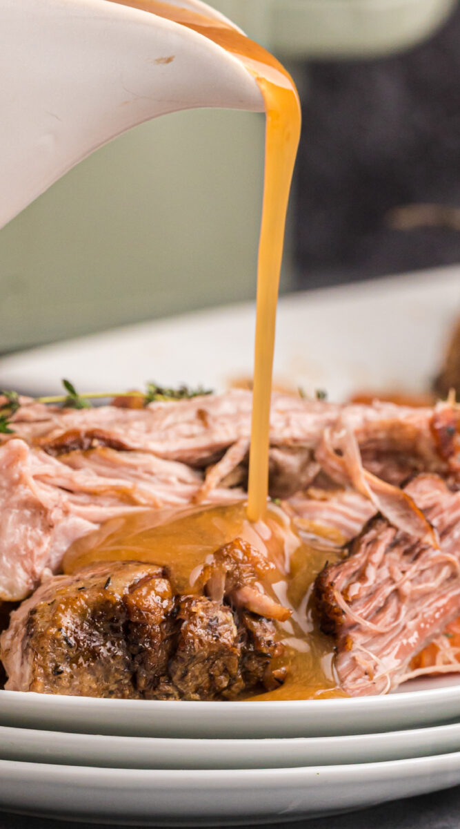 long image of shredded pork with gravy being poured over.