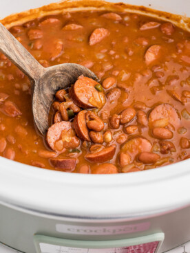 beanies and weenies in a crockpot with a wooden spoon in it.
