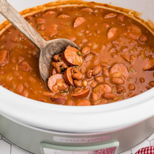 beanies and weenies in a crockpot with a wooden spoon in it.