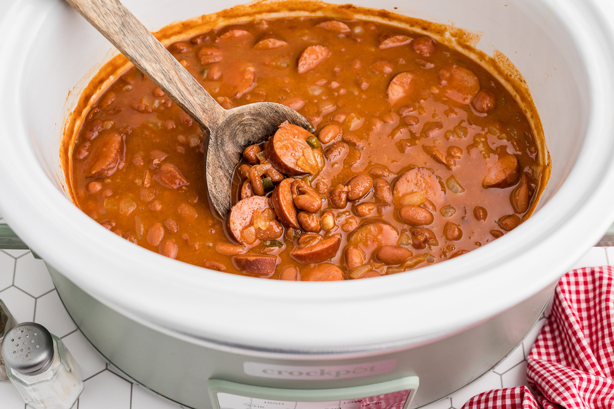 beanies and weenies in a crockpot with a wooden spoon in it.