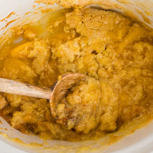 crockpot with peach cobbler with some dished out.