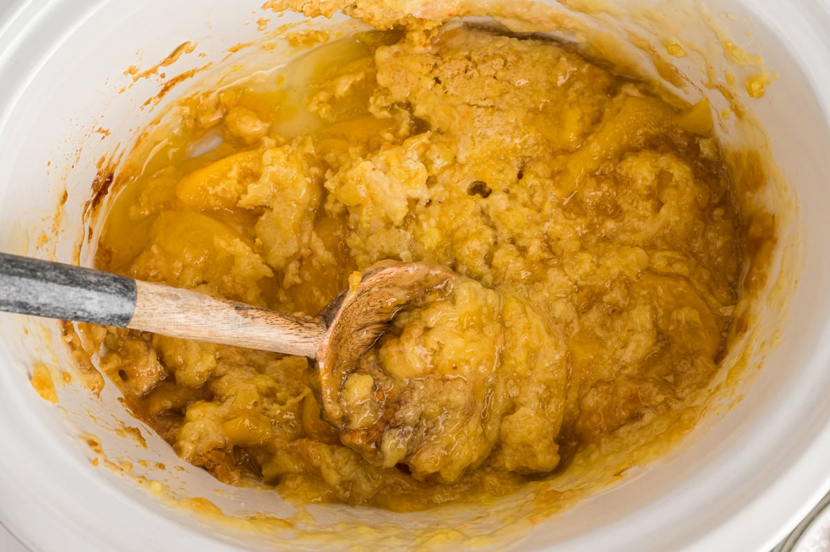 crockpot with peach cobbler with some dished out.