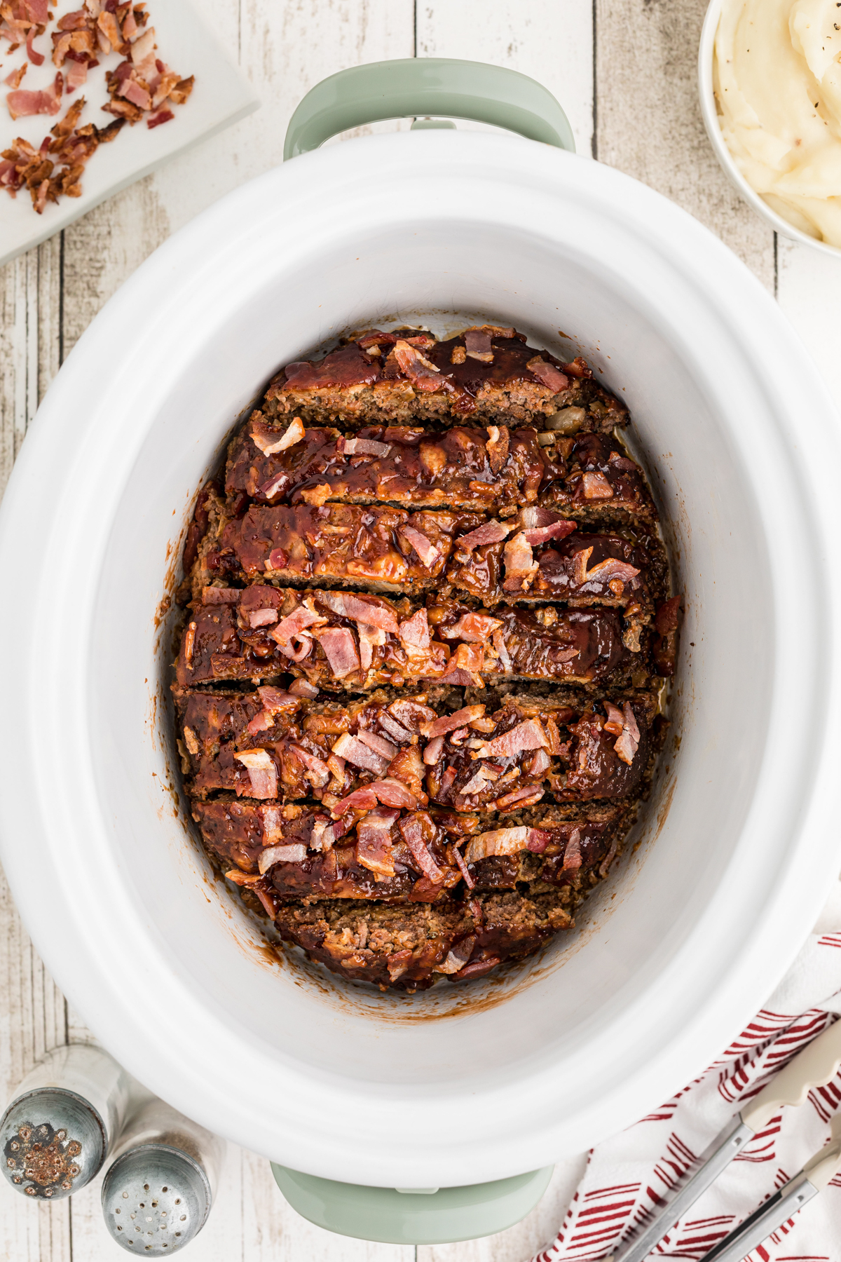 Cooked and sliced bacon barbecue meatloaf in a slow cooker.
