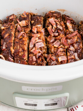 sliced meatloaf in a green slow cooker.
