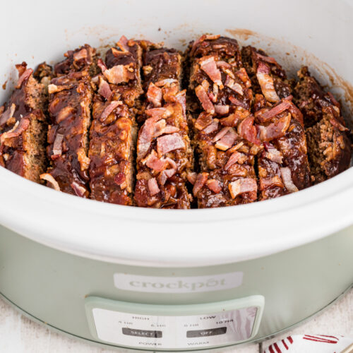 sliced meatloaf in a green slow cooker.