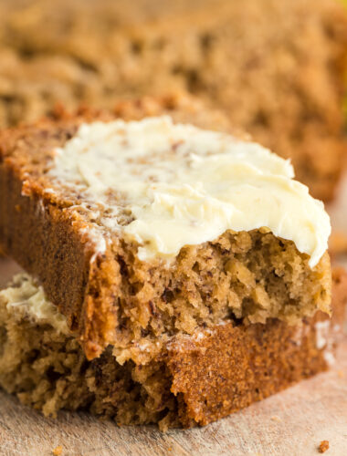 2 pieces of banana bread with butter on top of one.