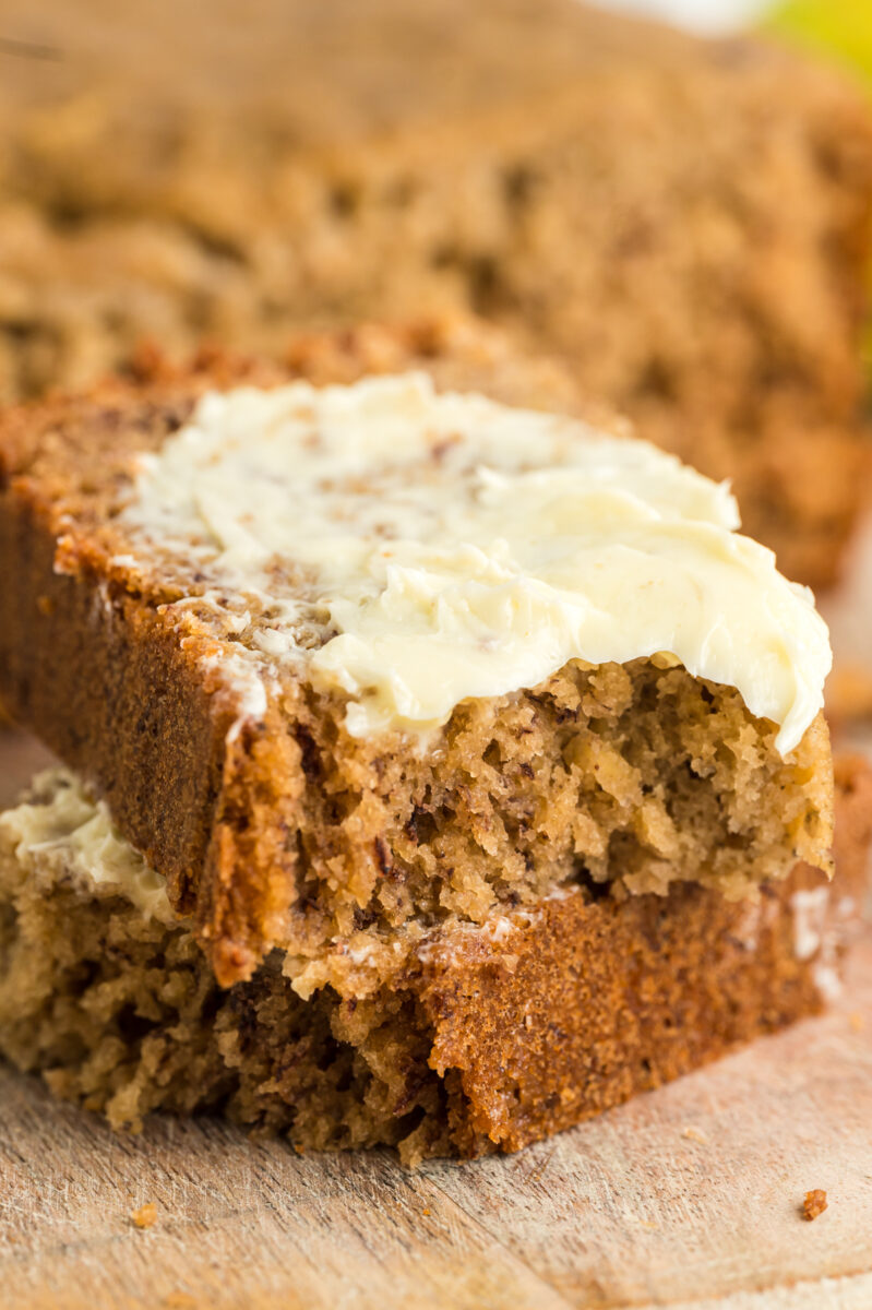 2 pieces of banana bread with butter on top of one.