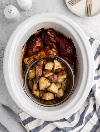 BBQ chicken and potaotes in a white slow cooker.