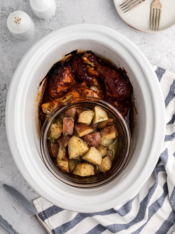 BBQ chicken and potaotes in a white slow cooker.