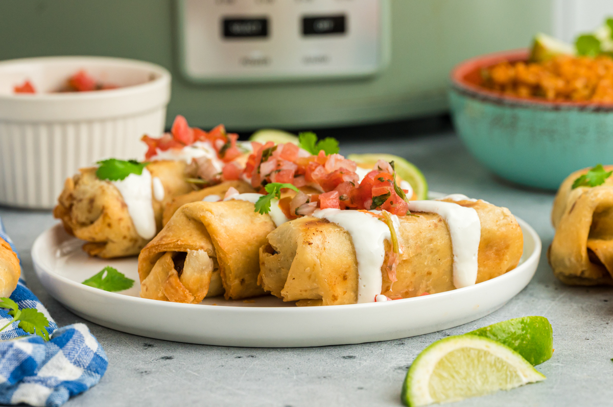 plate of beef chimichangas with sour cream and salsa.