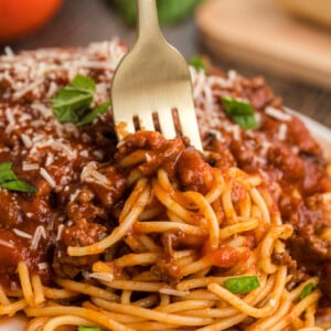 Spaghetti bolognese on a plate with a fork in it.
