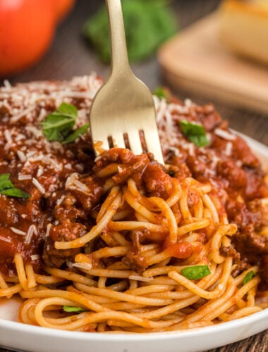 Spaghetti bolognese on a plate with a fork in it.
