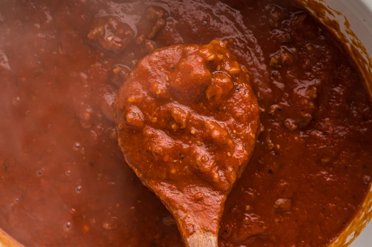 Close up of bolognese sauce on a wooden spoon.