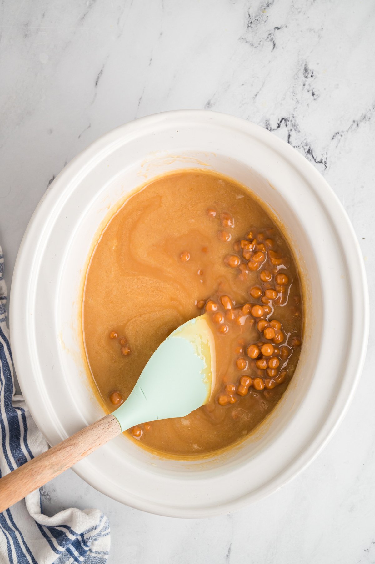 spatula stirring caramel in a slow cooker.