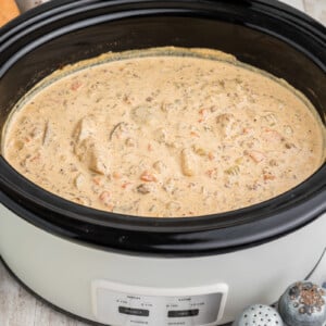 side view of cheeseburger soup in a black slow cooker.