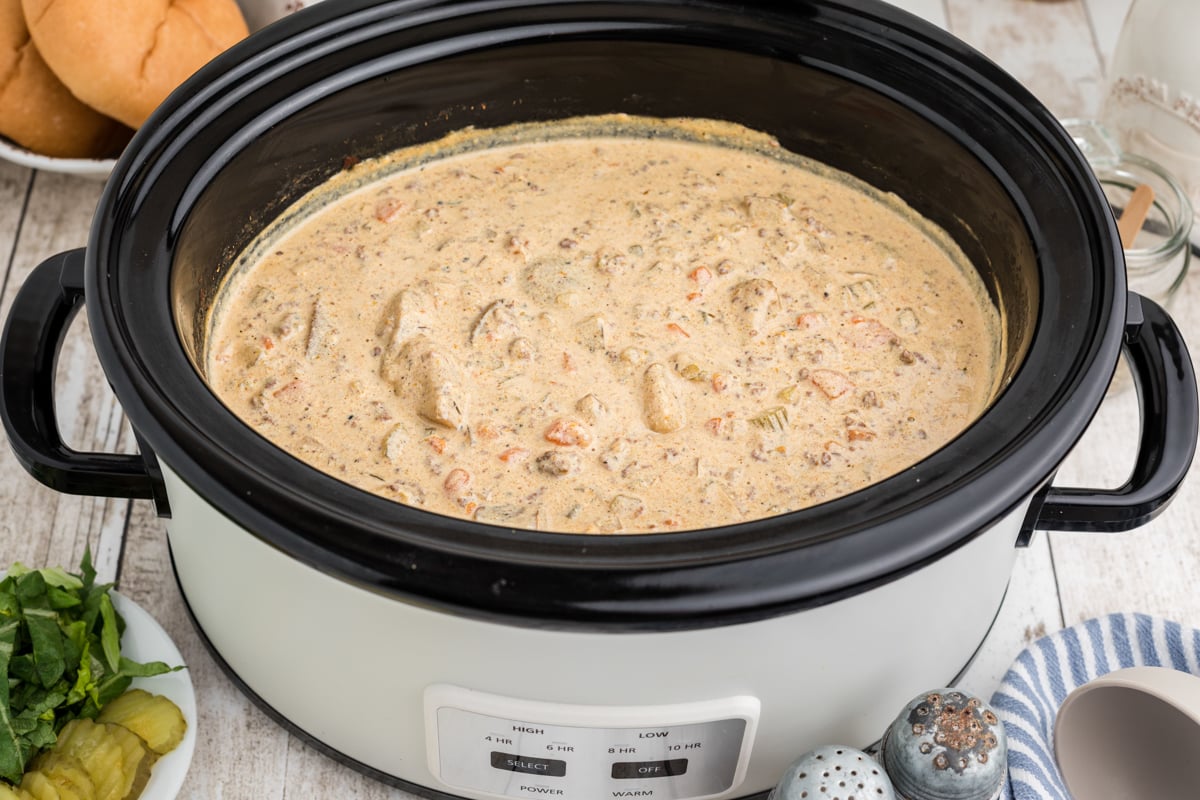 side view of cheeseburger soup in a black slow cooker.