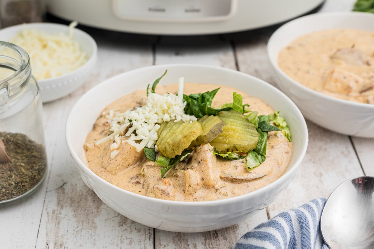 Bowl of cheeseburger soup in front of a slow cooker.