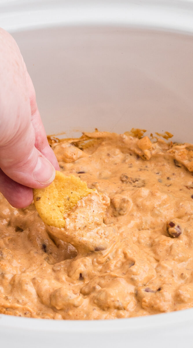 close up of chili cheese dip with a frito dipping in it.
