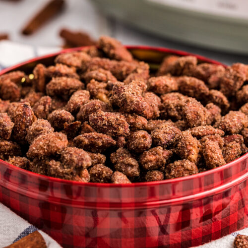 close up of cinnamon almonds in a red and black tin.