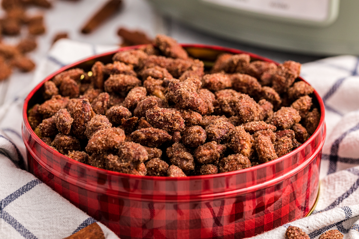 close up of cinnamon almonds in a red and black tin.