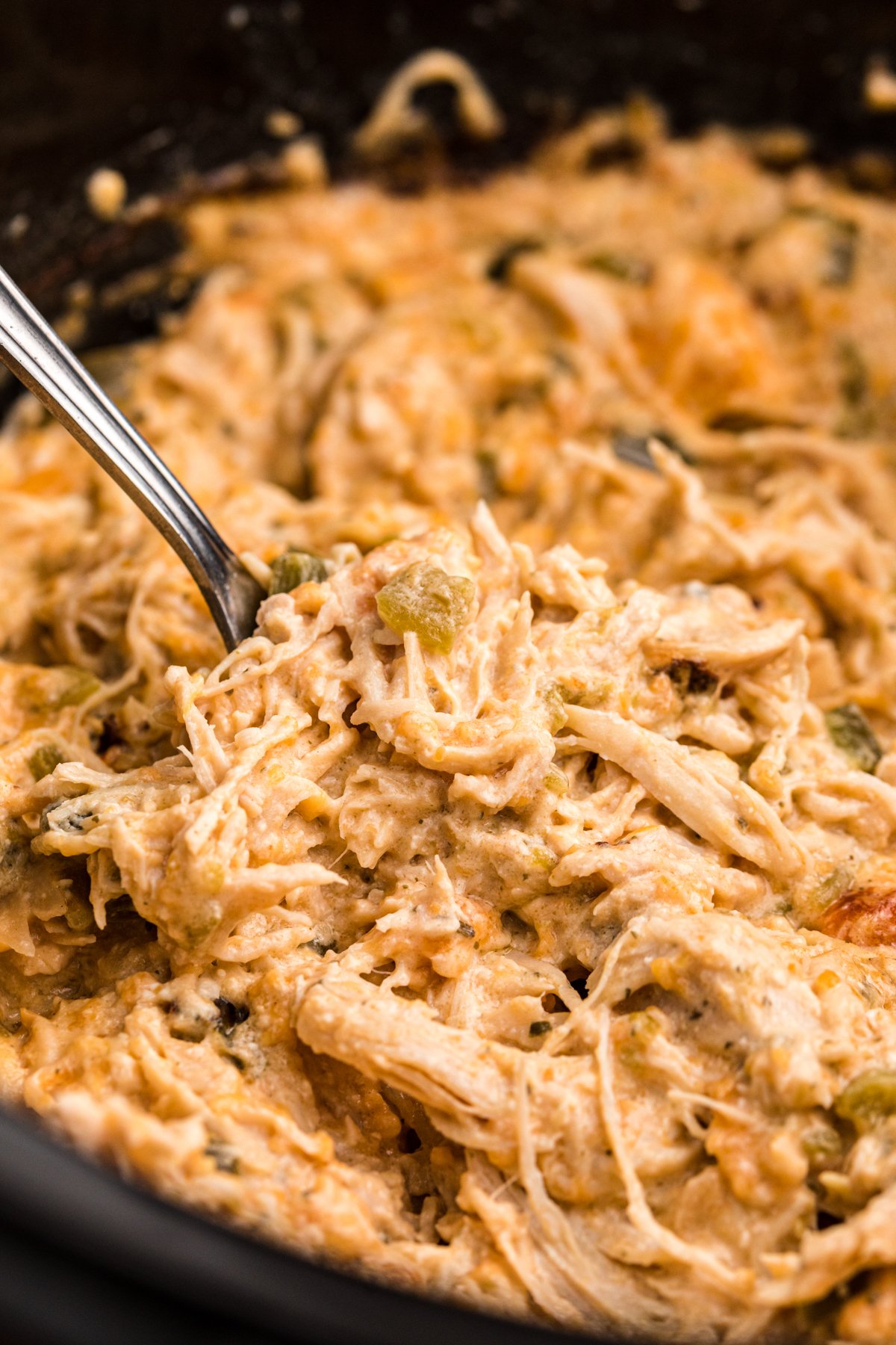 jalapeno popper chicken in a slow cooker with a fork in it.