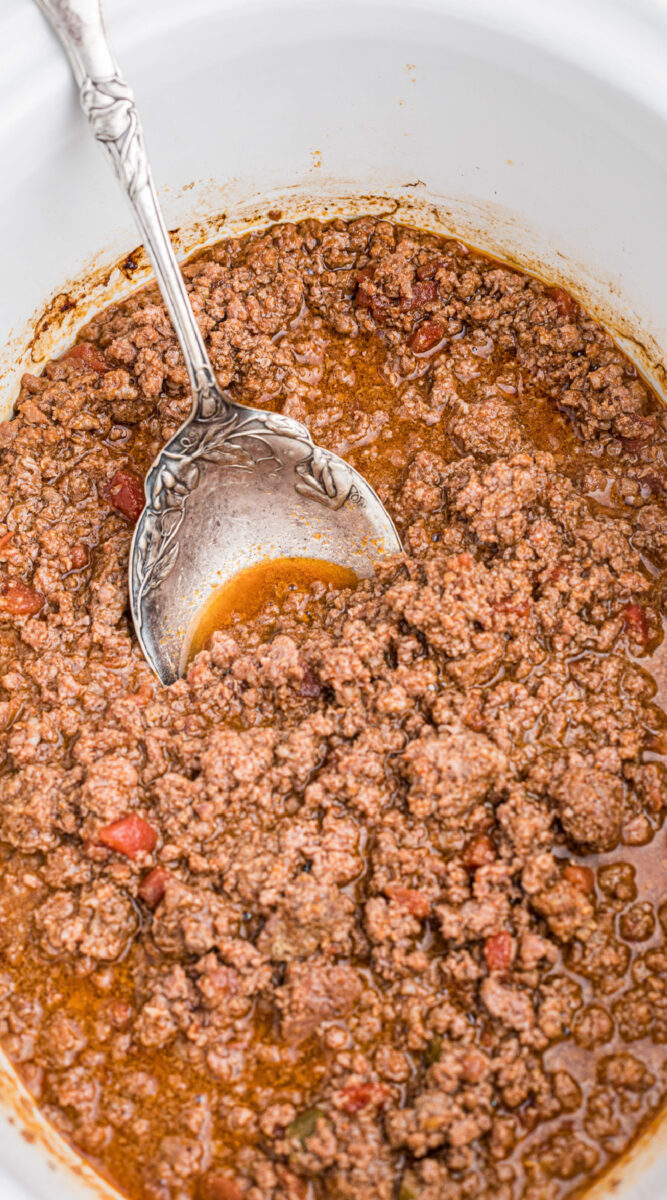 long image of venison taco meat with a spoon in it.