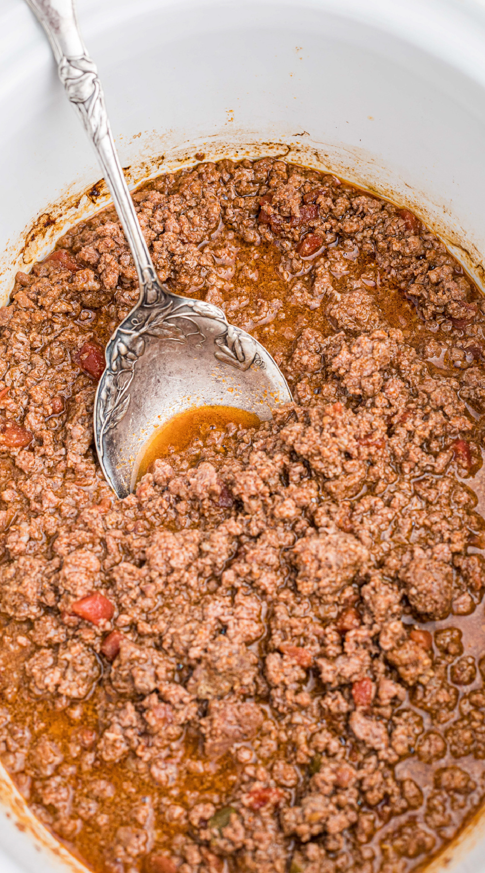 long image of venison taco meat with a spoon in it.