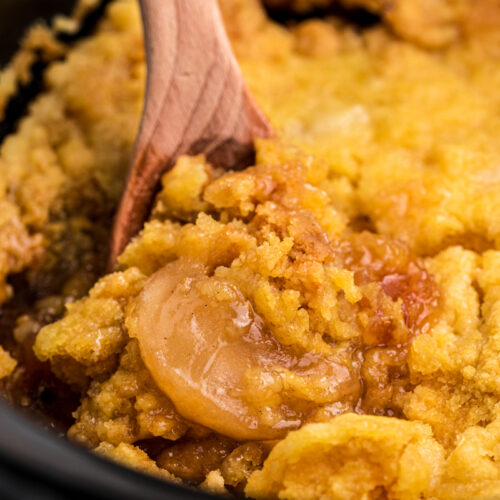 close up of apple dump cake on a wooden spoon.