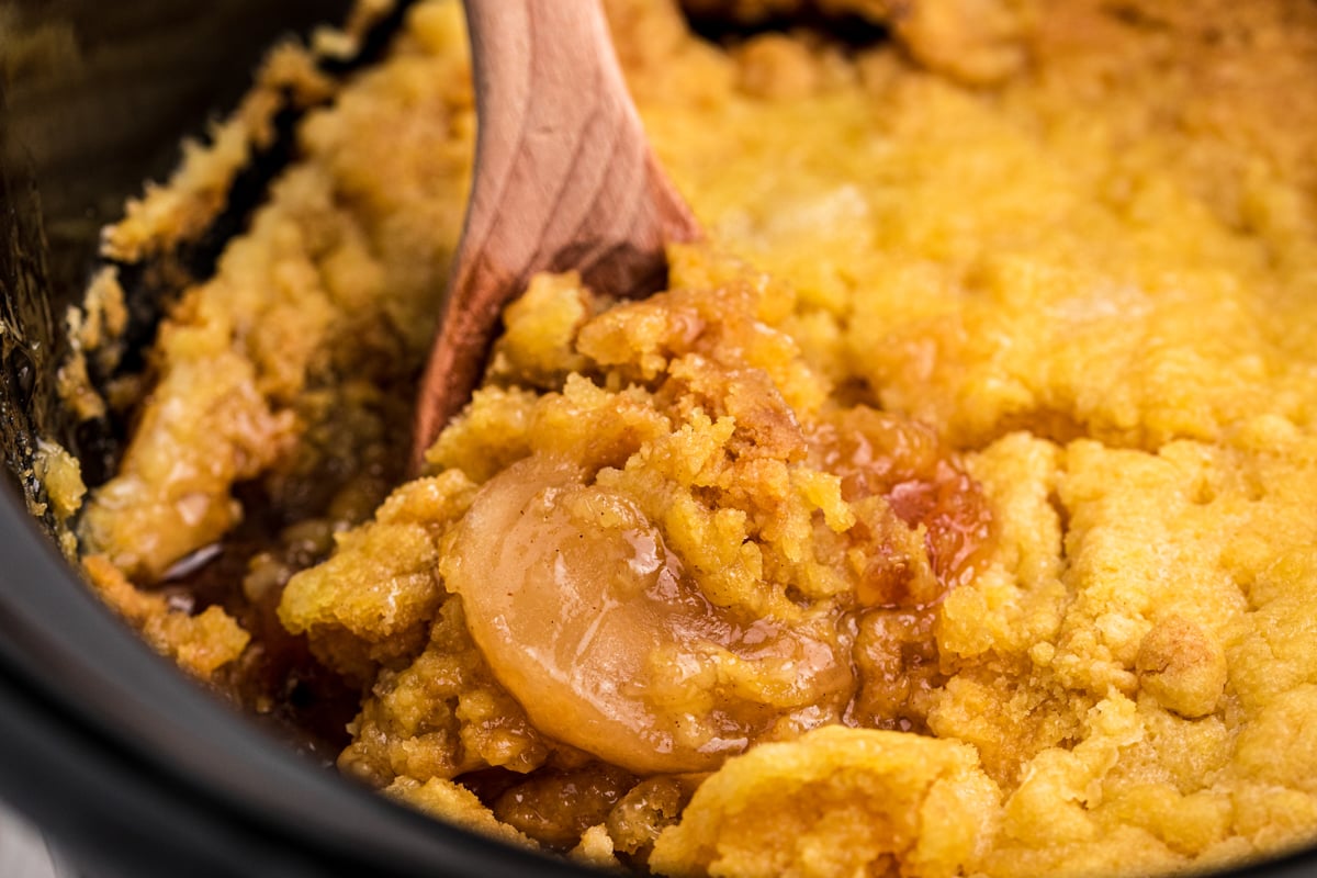 close up of apple dump cake on a wooden spoon.