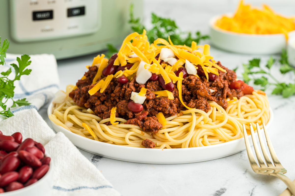 Chili on spaghetti on a white plate.