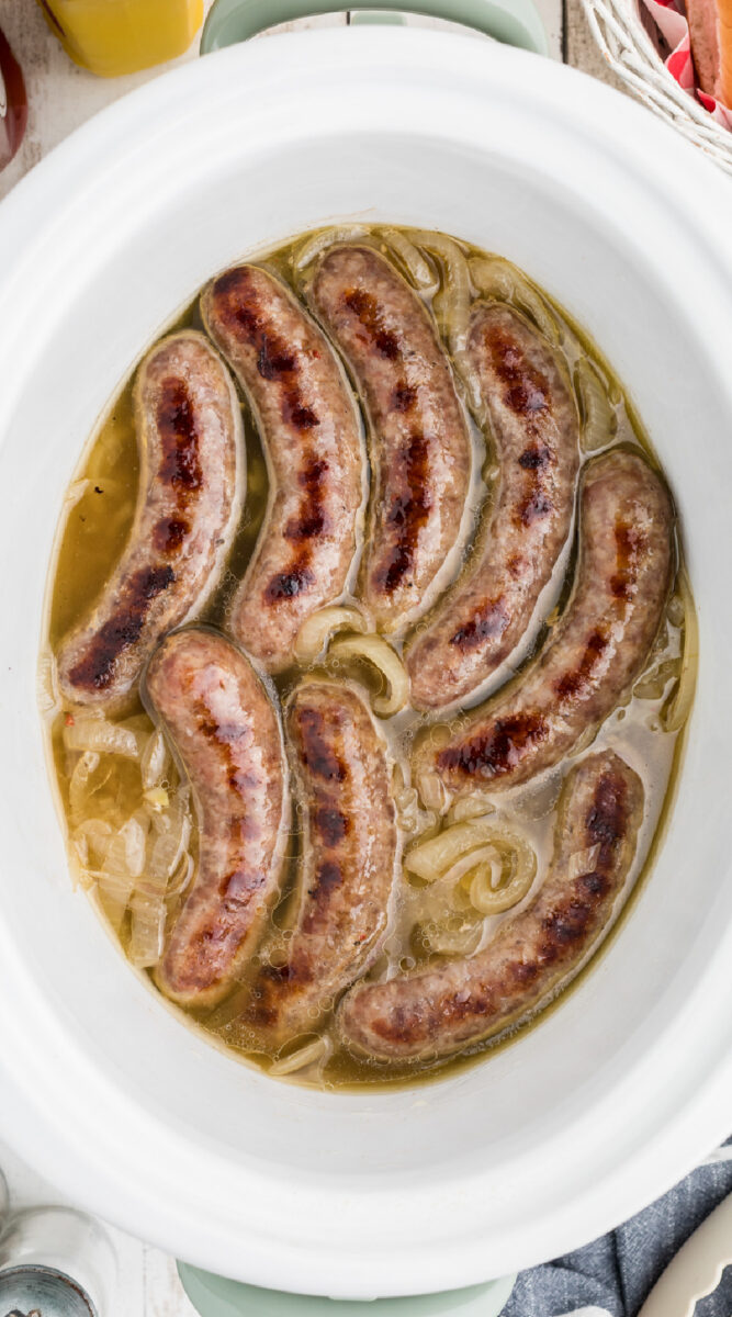 long image of hot dog brats in a slow cooker.