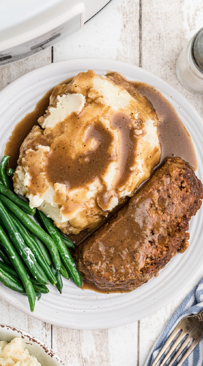 Long image of lipton meatloaf on a plate with potatoes and beans.