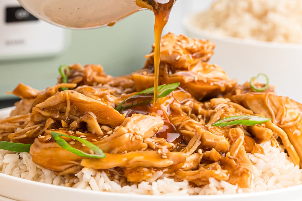 chicken and rice with sauce being poured over.