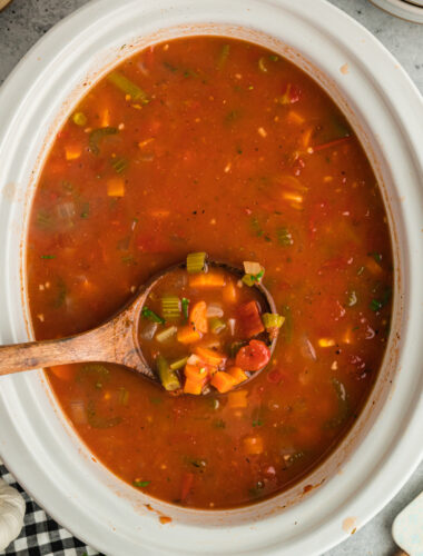 Vegetable soup in a slow cooker on a wooden spoon.