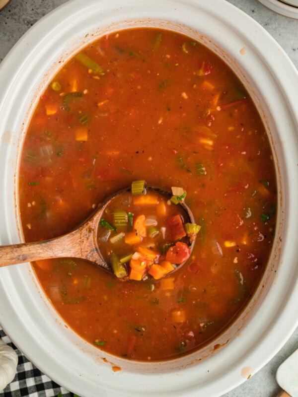Vegetable soup in a slow cooker on a wooden spoon.