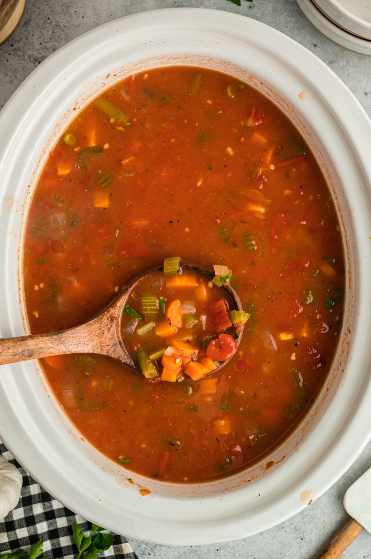 Vegetable soup in a slow cooker on a wooden spoon.