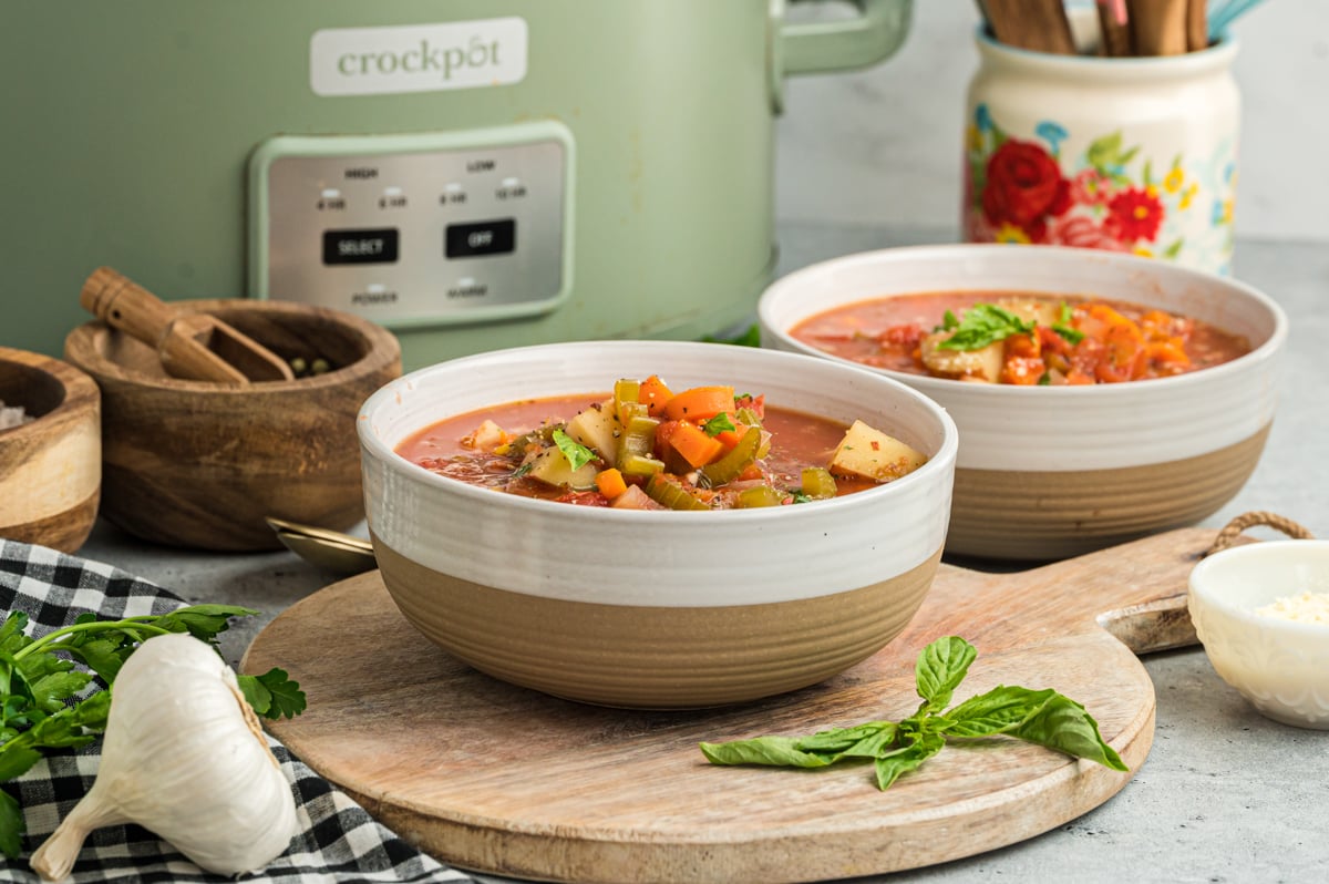 bowls of vegetable soup in front of a slow cooker.