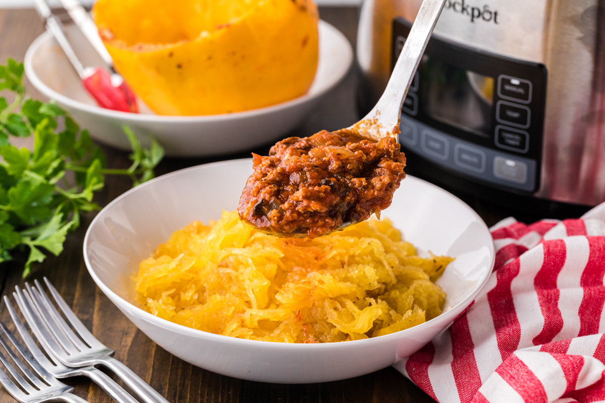 Meat sauce being poured on spaghetti squash.