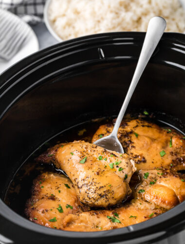 Brown sugar chicken breasts in a slow cooker on a spatula.