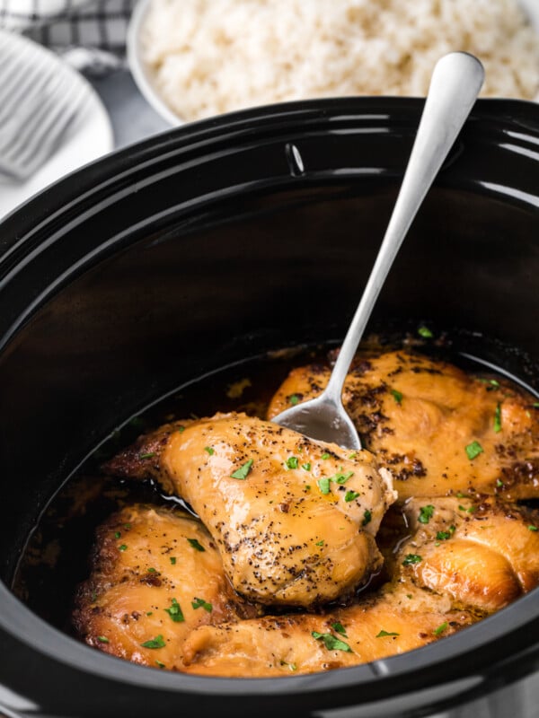 Brown sugar chicken breasts in a slow cooker on a spatula.