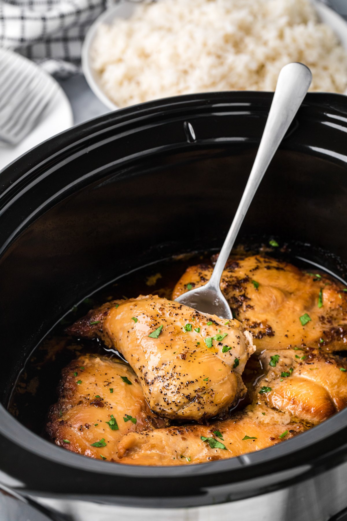 Brown sugar chicken breasts in a slow cooker on a spatula.