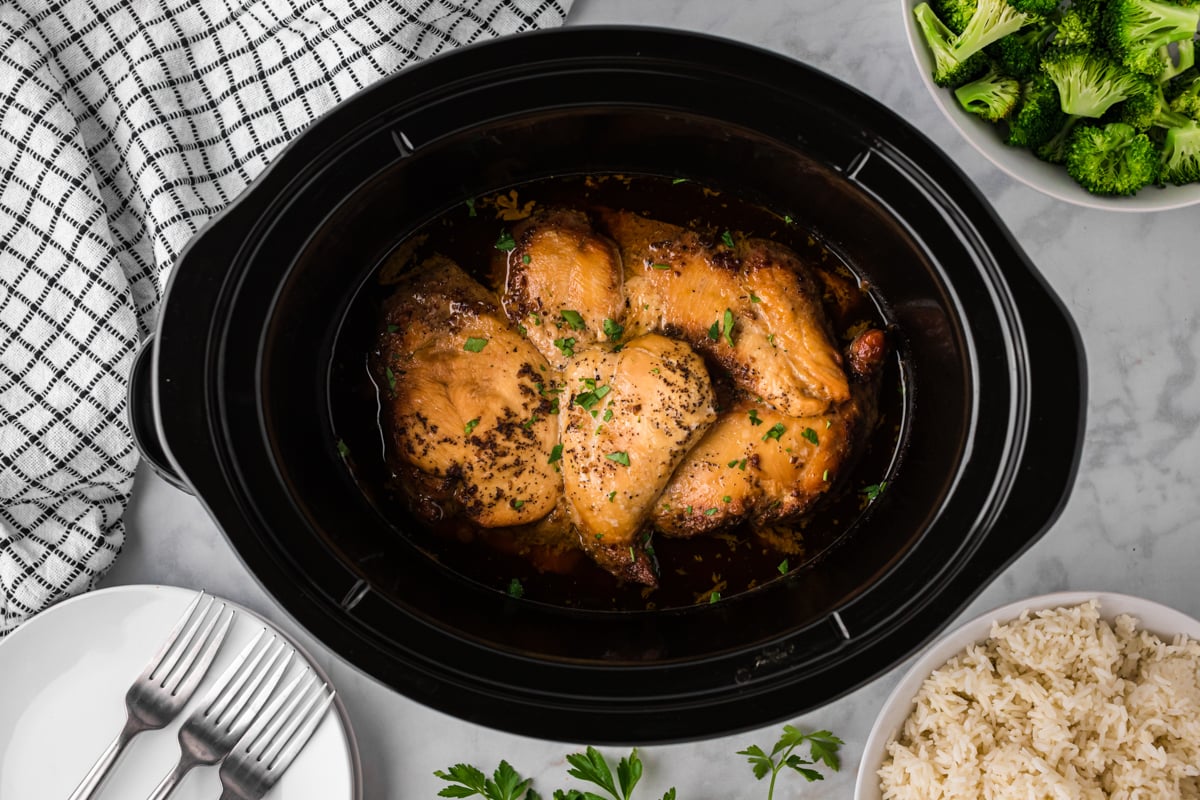 overhead shot of brown sugar chicken in a black slow cooker.