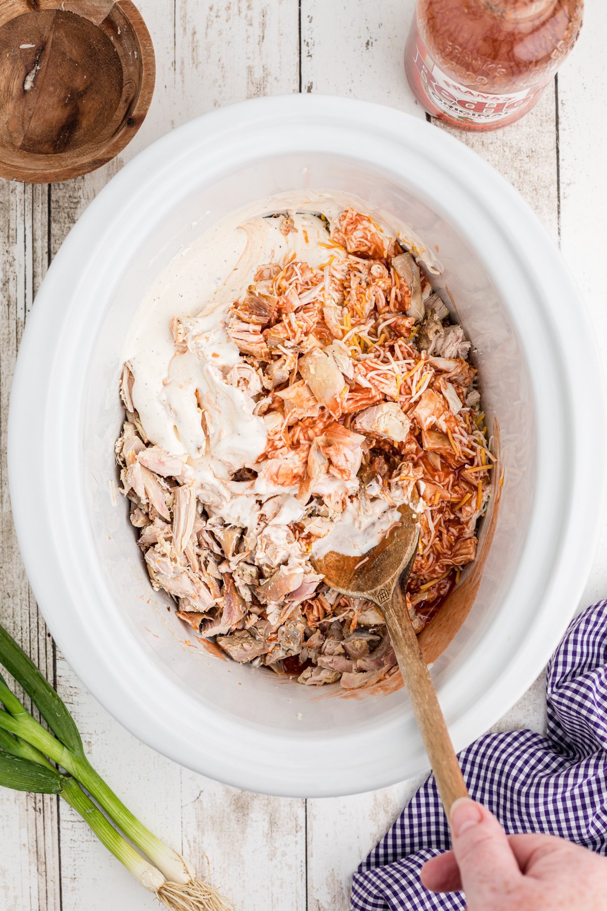 Ingredient being mixed together in a crockpot for buffalo dip,
