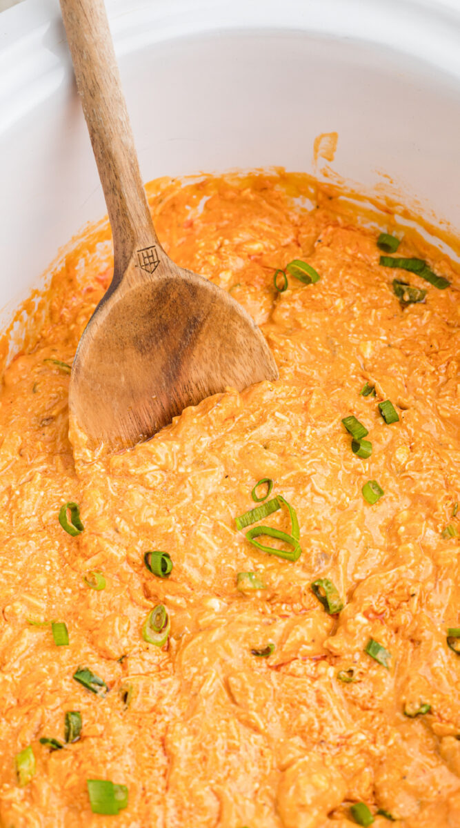 long image of buffalo chicken dip with wooden spoon in it.