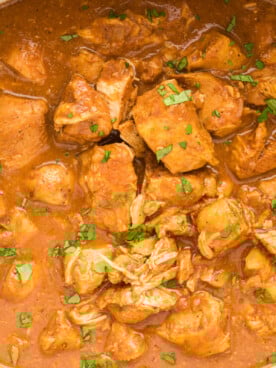 butter chicken cubes in a slow cooker with cilantro.